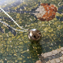 Load image into Gallery viewer, Silver bell pendant on a chain against a mosaic background
