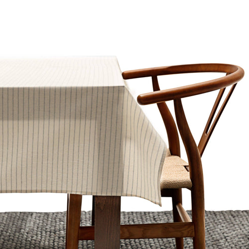 Beige tablecloth on a wooden dining table with a chair in the background