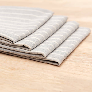 Stack of folded gray and white striped towels on a wooden surface