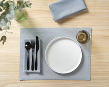 Load image into Gallery viewer, Dining table setting with a white plate, black cutlery, and gray placemat on a wooden surface.
